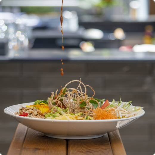 salade-siam-thailande.jpg Une délicieuse salade thaïlandaise du restaurant Siam, vue de profil sur laquelle on verse de la vinaigrette