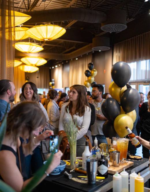 Plusieurs personnes célèbrent le 10ème anniversaire du restaurant Siam avec des cocktails et des ballons.