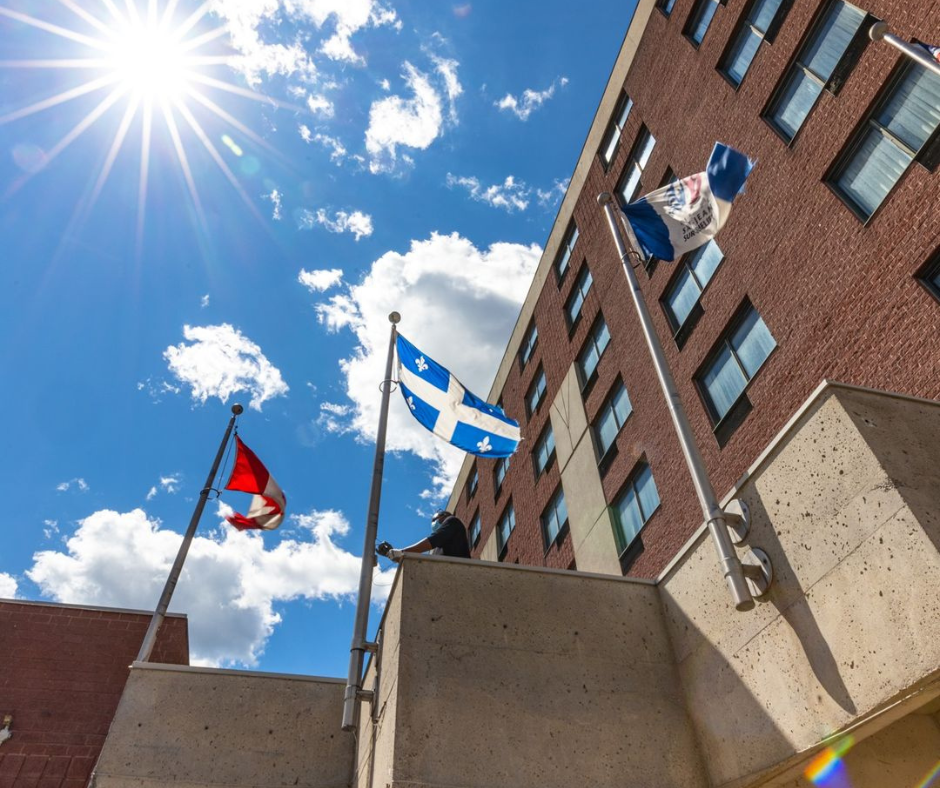 Hotel avec drapeaux canadien et québécois vu du bas avec ciel bleu