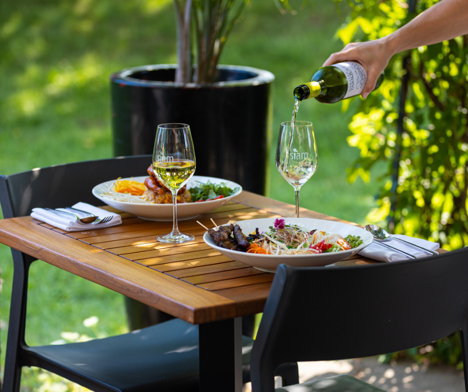 Table avec assiettes et verres de vin dans une terrasse ensoleillée et verdoyante